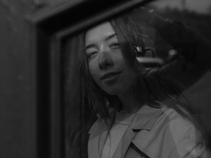 A person in a minimalist workspace looking out the window thoughtfully.